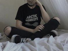 a woman sitting on top of a bed next to a white curtain and wearing black leggings