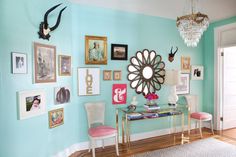 a living room with blue walls and pictures on the wall, including a chandelier