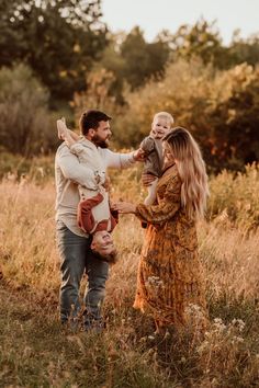 a man and woman are holding their child in the field