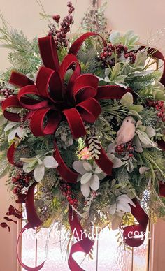 a christmas wreath with red ribbons and greenery hanging from the front door, on a window sill