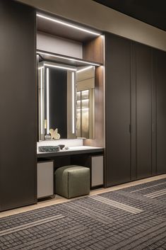 a bathroom with a vanity, mirror and stool next to it in front of a closet