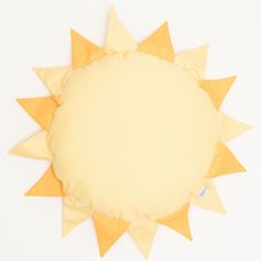 a yellow and white sun shaped pillow on a white surface with a blank space in the middle