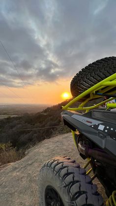 the sun is setting behind two atvs