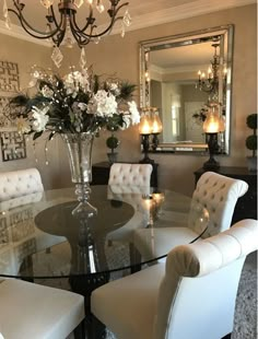 a dining room table with white chairs and a chandelier