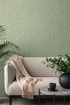 a living room with a couch, table and potted plants