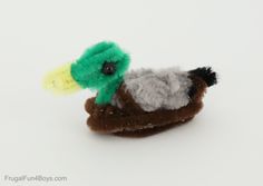 a small stuffed bird sitting on top of a brown shoe with green and white feathers