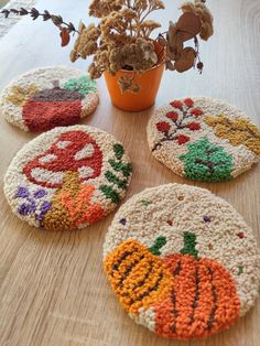 four crocheted coasters sitting on top of a table next to a potted plant