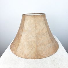 a lamp shade sitting on top of a white cloth covered table next to a wall