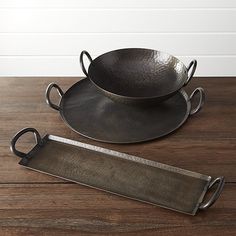 two metal serving trays with handles on a wooden table