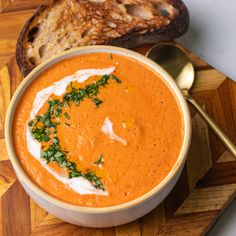 a bowl of tomato soup with bread on the side