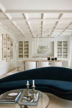 a living room filled with furniture next to a table and bookshelves on the wall