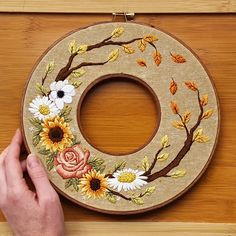 someone is working on an embroidered wreath with sunflowers and roses