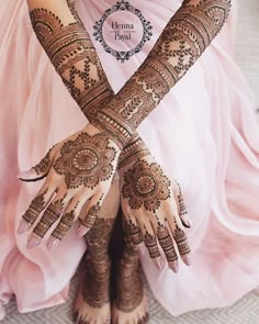 a woman with henna tattoos on her hands and feet, sitting in a pink dress