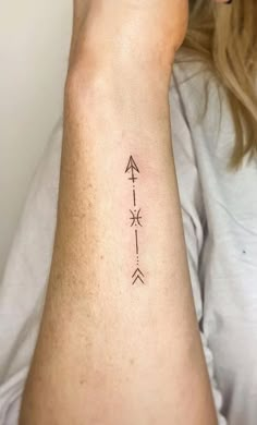 a woman's arm with an arrow tattoo on the left side of her arm