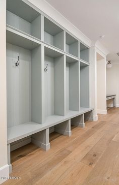 a row of empty white shelves sitting on top of a hard wood floored floor