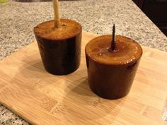 two brown cups sitting on top of a wooden cutting board