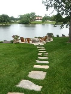 a stone path in the grass leading to a lake