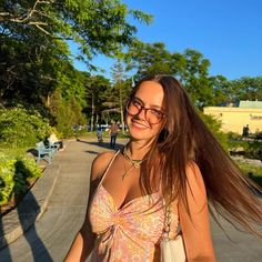 a woman with long hair and glasses walking down the street