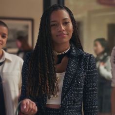 a woman with long braids standing in front of other people and looking at the camera