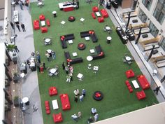 an overhead view of a lawn with red and black couches, tables and umbrellas