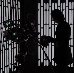 a woman standing next to a camera in front of a wall with lights on it