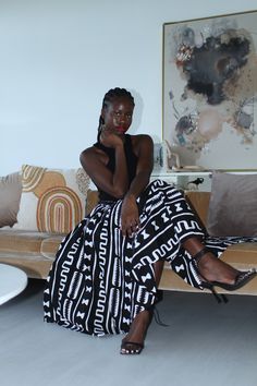 a woman sitting on top of a couch in a living room next to a painting