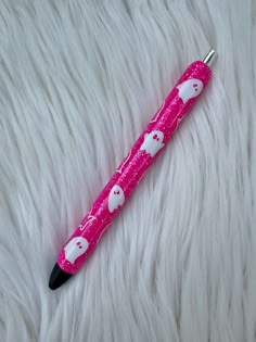 a pink pen with white hearts on it sitting on top of a fur covered surface