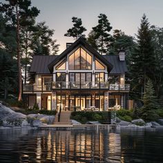 a large house sitting on top of a lake next to a lush green forest covered hillside