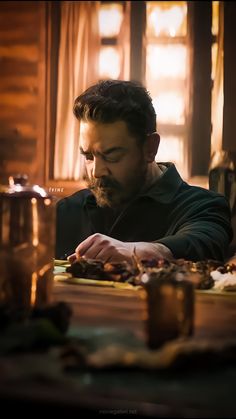 a man sitting at a table with food in front of him and candles on the table