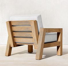 a wooden chair sitting on top of a floor next to a white pillow in front of a wall