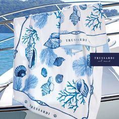 a towel hanging on the side of a boat with sea shells and corals printed on it