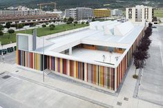 an aerial view of a multicolored building with mountains in the background