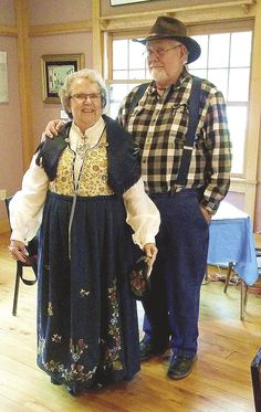 an older man and woman standing next to each other in a room with wooden floors