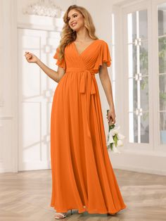 a woman wearing an orange bridesmaid dress with short sleeves and a tie around the waist