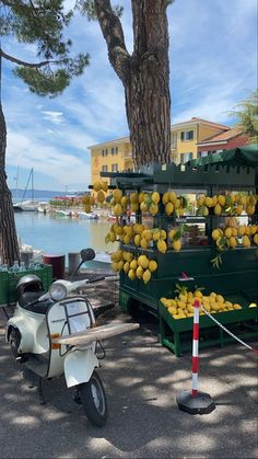 a scooter parked next to a fruit stand on the side of a road