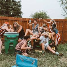 a group of people sitting on top of a green lawn next to a wooden fence