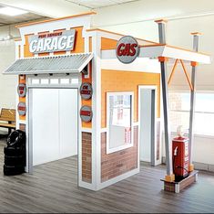 an orange and white garage with gas pumps on the floor next to it's entrance