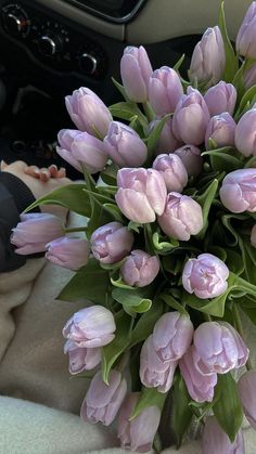 a bouquet of pink tulips sitting on top of a blanket in a car