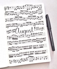 an open notebook with music notes and the words august written on it next to a pen