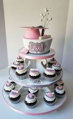 a tiered cake with cupcakes on the bottom and pink decorations around it