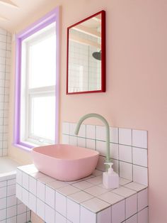 a bathroom with a pink bowl sink next to a window