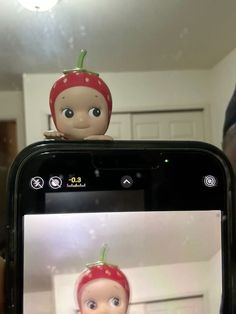 a person holding up a cell phone with an image of a baby doll on it