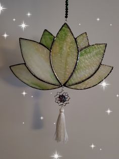 a stained glass flower hanging from the ceiling with beads and tassels on it