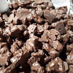 a pile of chocolate pieces sitting on top of a metal pan next to a spoon