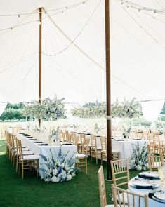 an outdoor tent with tables and chairs set up for a formal dinner or reception in the grass