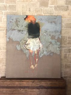 a painting on a brick wall above a wooden dresser