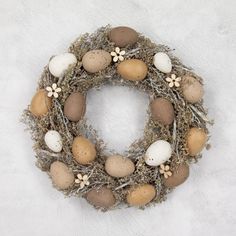 a wreath made out of eggs and twigs on a white surface with flowers in the center