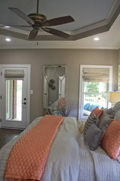 a bedroom with a bed, mirror and ceiling fan