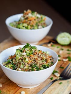 two white bowls filled with food on top of a wooden cutting board next to a knife and fork