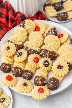 some cookies are on a white plate with chocolates and sprinkles around them